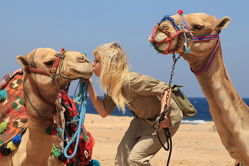 woman kissing a camel in the desert