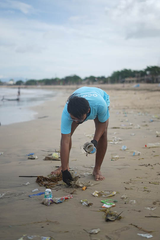 man picking up plastic waste in the shore